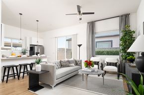 Omaha townhouse for rent - A modern living room with a grey sofa, a grey coffee table, and a white ceiling fan.