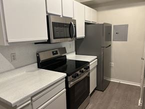 Euless apartment for rent - a kitchen with white cabinets and black appliances and a refrigerator