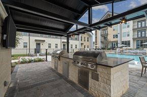 Buda apartment for rent - A patio with a grill and a pool in the background.