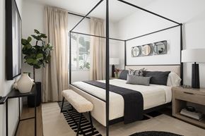 Phoenix apartment for rent - A modern bedroom with a four poster bed and a plant on the side table.