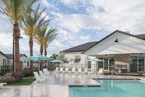 Surprise apartment for rent - A pool area with palm trees and a white building.