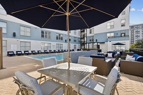 Dallas apartment for rent - A large umbrella shades a table and chairs on a patio.