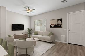 Phoenix apartment for rent - A living room with a white couch, a green cushion, a white coffee table, a white dining table, a white rug, a white ceiling fan, a flat screen TV, a plant, and a picture on the wall