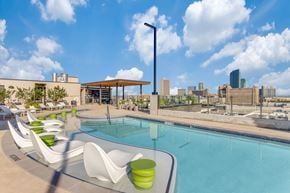 Fort Worth apartment for rent - A pool area with white chairs and green cushions.