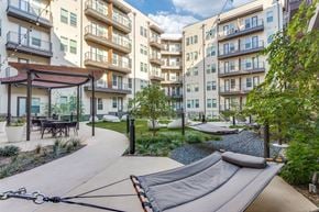 Fort Worth apartment for rent - A playground with a slide in the middle of a courtyard surrounded by apartment buildings.