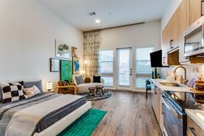 Fort Worth apartment for rent - A bedroom with a large bed and a kitchen area in the same room.