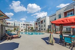 Conroe apartment for rent - A pool area with a striped umbrella and chairs.