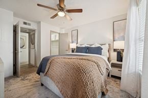 Austin apartment for rent - A bedroom with a bed covered in a brown blanket and a ceiling fan.