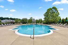 Howell townhouse for rent - an oval swimming pool with chairs around it and trees in the background