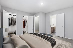 Stephenville apartment for rent - A bedroom with a large bed and a closet with clothes hanging.