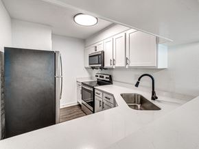 Oklahoma City apartment for rent - A kitchen with a black refrigerator, white countertops, and stainless steel appliances.