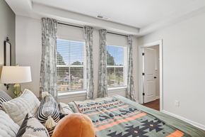 Charlotte townhouse for rent - A bedroom with a large bed and a window with a view of the outside.