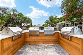 Dallas apartment for rent - two bbq grills in the backyard of a home with a pool in the background