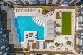 Plano apartment for rent - A large swimming pool surrounded by a patio area with chairs and a small grassy area.
