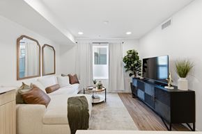 Jackson apartment for rent - A modern living room with a white couch, a black entertainment center, and a large window.