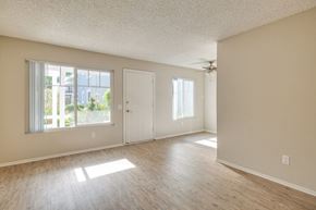 Oceanside apartment for rent - A room with a ceiling fan and a door leading to a balcony.