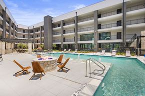 Katy apartment for rent - a swimming pool with chairs and a fire pit in front of a hotel