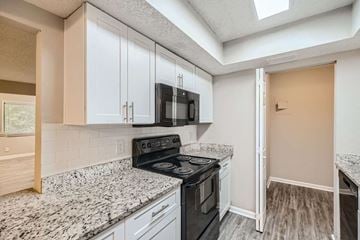 Atlanta apartment for rent - A kitchen with a black stove top oven and white cabinets.