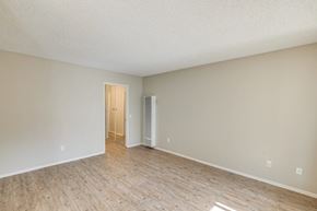 Oceanside apartment for rent - A room with a wooden floor and a door leading to another room.