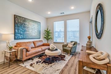 Melissa apartment for rent - A living room with a brown leather couch, a white coffee table, and a large painting on the wall.