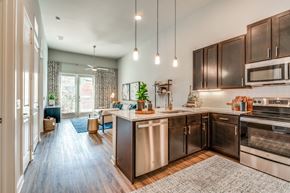 Fort Worth apartment for rent - A modern kitchen with dark wood cabinets and stainless steel appliances.