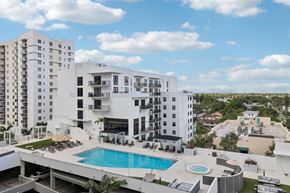 Miami apartment for rent - A large white building with a pool in the foreground.