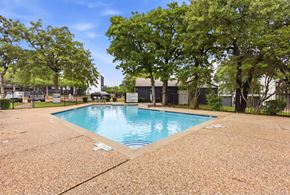 Fort Worth apartment for rent - A pool surrounded by trees and a fence.