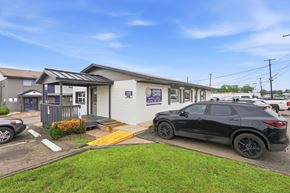 Stephenville apartment for rent - A black SUV is parked in front of a building with a blue sign that reads "CARS 4 LIFE."