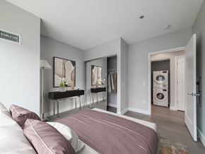 Chicago apartment for rent - A bedroom with a bed and a washing machine in the laundry area.