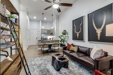 Dallas apartment for rent - A living room with a brown leather couch and a wooden bookshelf.