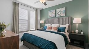 West Melbourne apartment for rent - A bedroom with a bed, nightstand, and a plant.