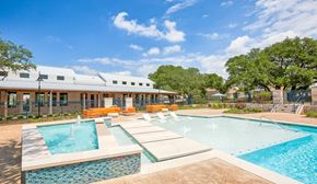 Round Rock apartment for rent - A swimming pool with a waterfall and a building in the background.