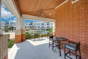 Lewisville apartment for rent - A patio with a table and chairs overlooks a pool and buildings.