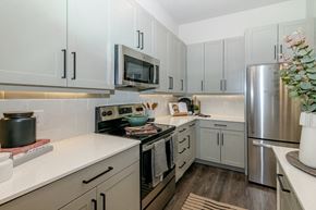 Dallas apartment for rent - a kitchen with white cabinets and stainless steel appliances