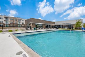 Dallas apartment for rent - A large swimming pool in front of a building with a sunny sky.