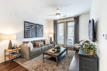 Stone Mountain apartment for rent - A living room with a grey couch, a coffee table, a television, and a large abstract painting on the wall.