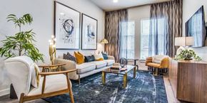 Fort Worth apartment for rent - A modern living room with a white sofa, wooden chairs, and a coffee table.