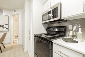 Dallas apartment for rent - A modern kitchen with a black stove top oven and microwave above it.
