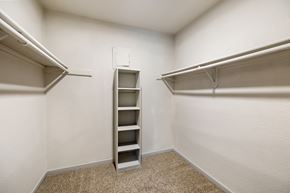 Houston apartment for rent - a spacious walk in closet with shelves and a mirrored closet door
