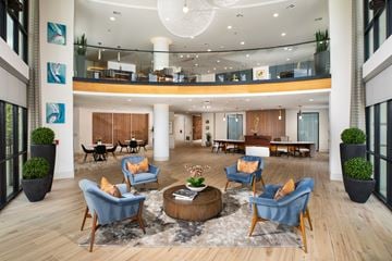 Houston apartment for rent - A large, modern living room with blue chairs and a coffee table.