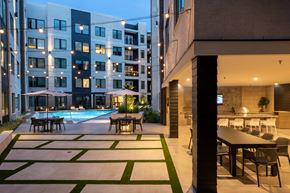 Houston apartment for rent - A modern building with a pool and a dining area.