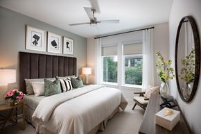 Houston apartment for rent - A bedroom with a large bed, a ceiling fan, and a mirror.