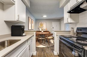 Dallas apartment for rent - an open kitchen and dining room with white cabinets and appliances and a table and chairs