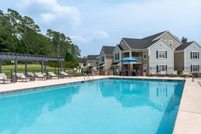 Aberdeen townhouse for rent - A large swimming pool in front of a building with a row of lounge chairs on the left.