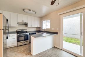 Oceanside apartment for rent - A kitchen with white cabinets and a black fridge.