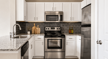 Dallas apartment for rent - A modern kitchen with white cabinets and stainless steel appliances.