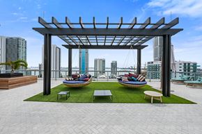 Miami apartment for rent - a rooftop lounge area with lounge chairs and a hammock with a view of the city