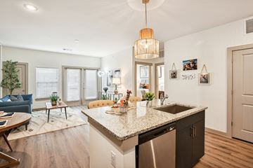 Katy apartment for rent - A kitchen with a granite countertop and a blue sofa in the living room.