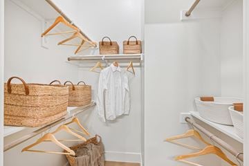 Denton apartment for rent - A white closet with clothes and baskets on shelves.
