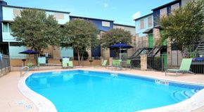San Antonio apartment for rent - a swimming pool with chairs and umbrellas next to a building
